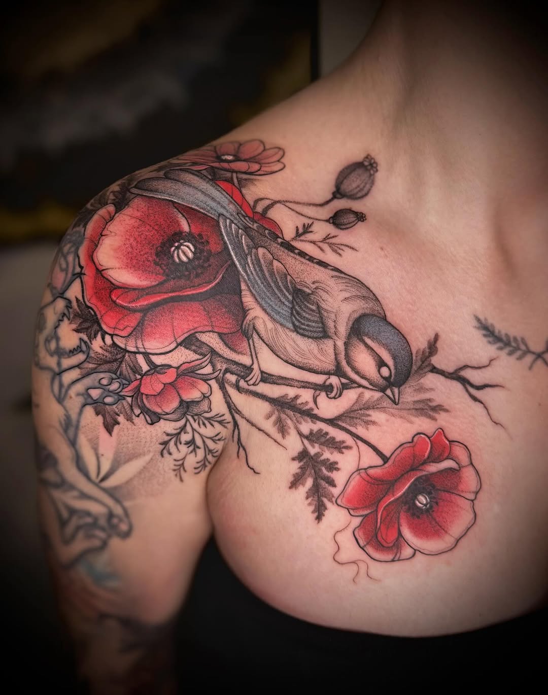 Detailed shoulder tattoo featuring a bee with red poppies and botanical elements in red and black ink.