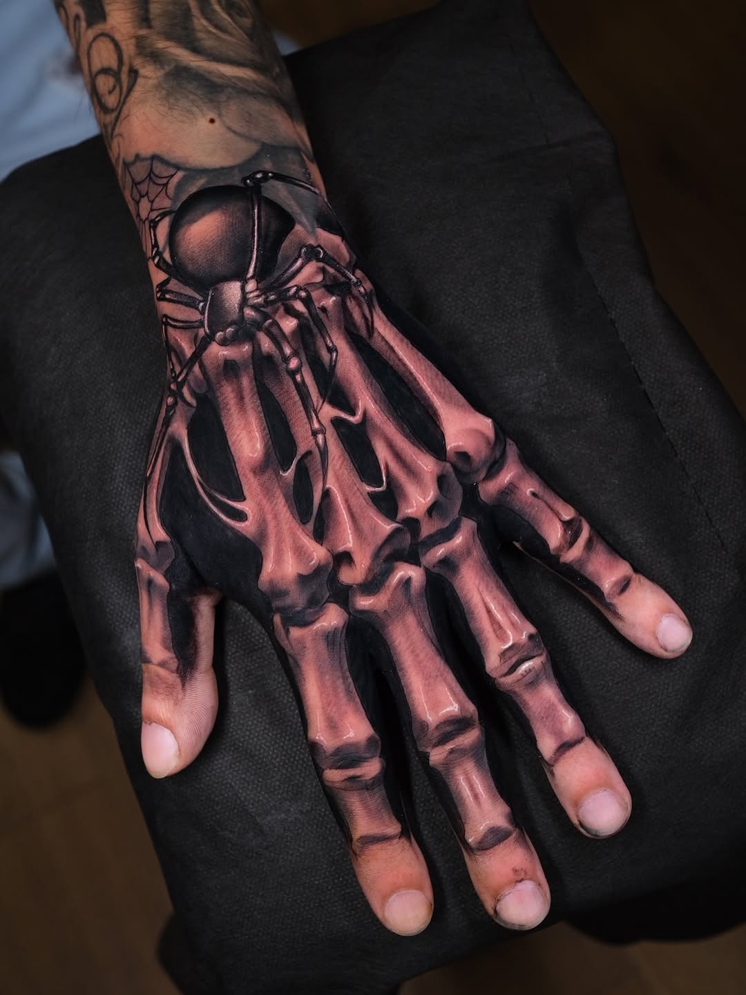 Detailed scarab beetle tattoo on hand with skeletal anatomy overlay, rendered in shades of brown and black with shading on the fingers and palm.