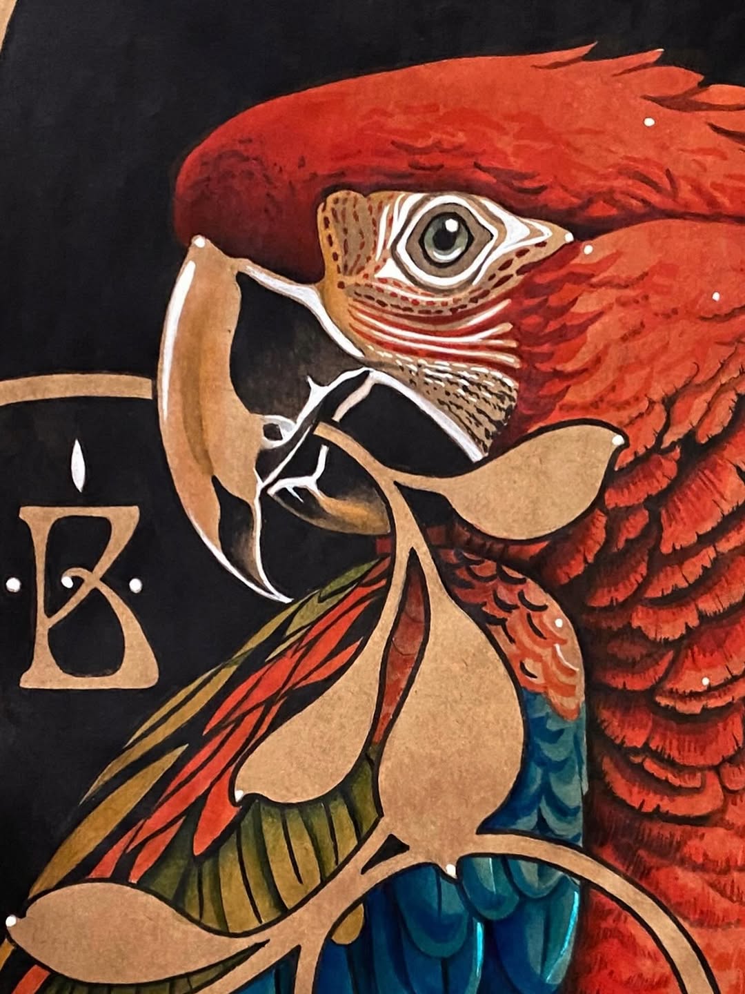 Colorful parrot head tattoo featuring vibrant red plumage, tan and blue wing details, and a distinctive eye, displayed on upper arm or shoulder.