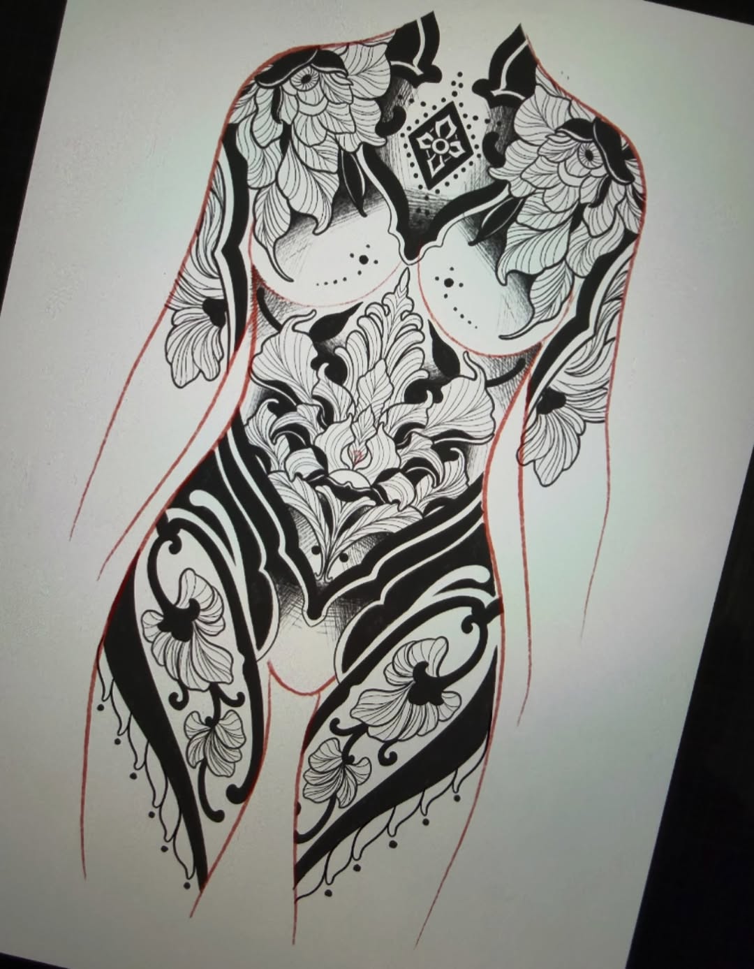 Detailed black ink full-body tattoo design sketch on white paper with ornamental floral patterns, geometric chest piece, and red outline showing body contours.