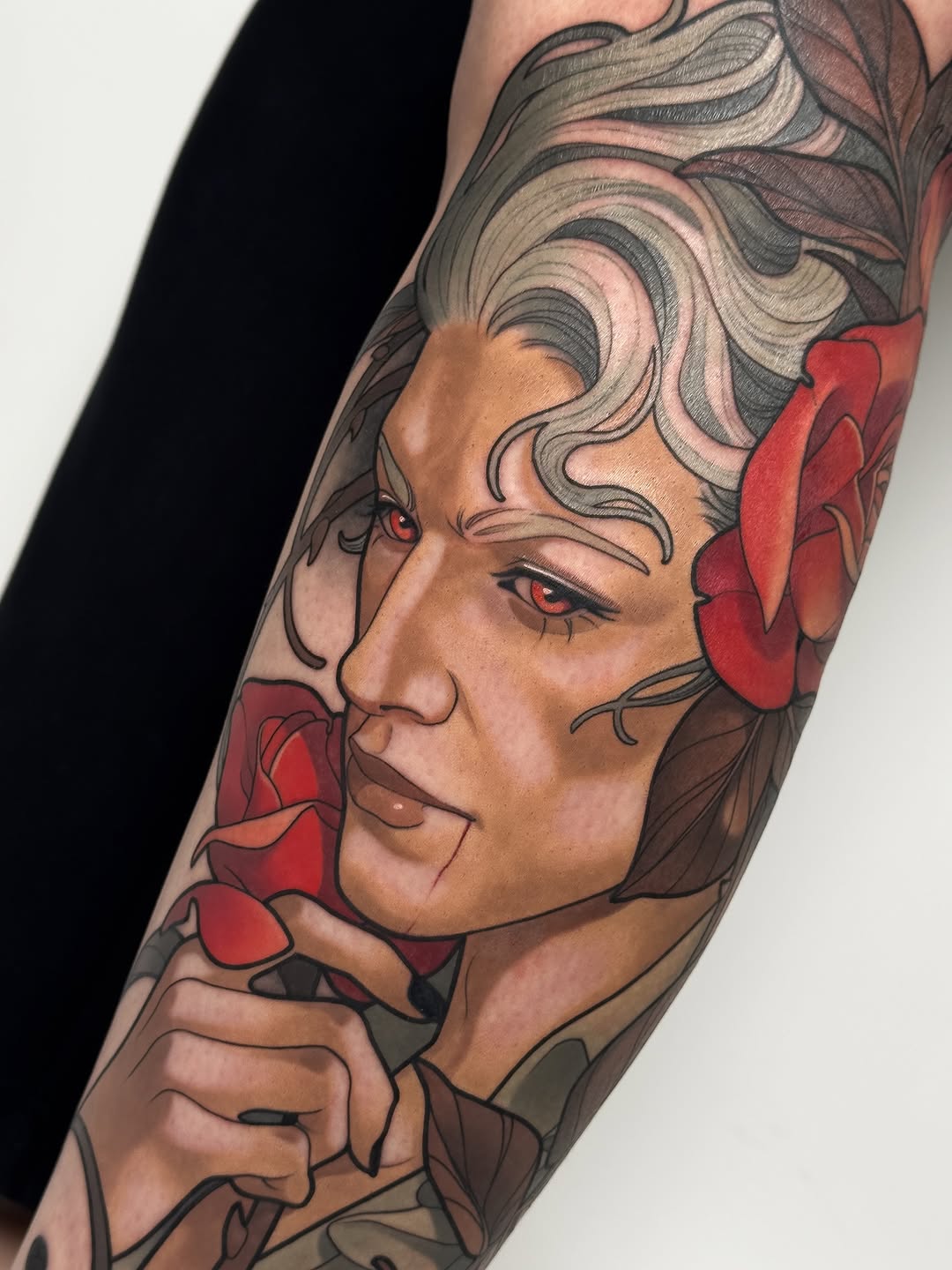 Colored shoulder tattoo featuring a woman's profile with styled hair, red flowers, and detailed facial features in browns, reds, and neutral tones.