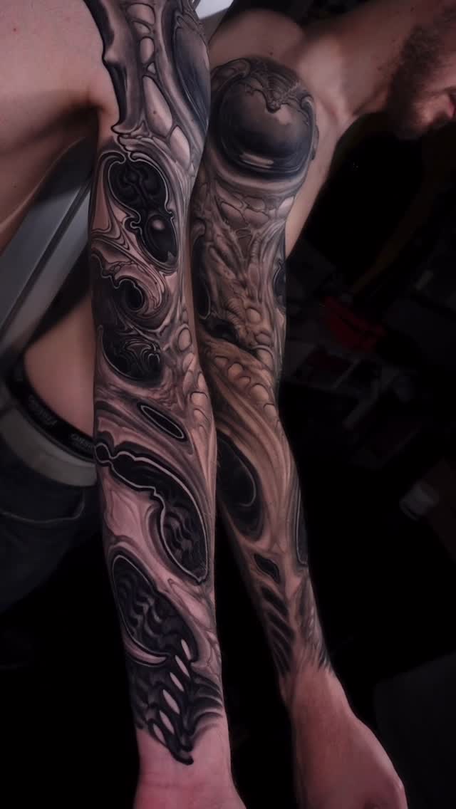 Full-length arm tattoo featuring intricate ornamental patterns and spherical designs in black and grey ink on pale skin.