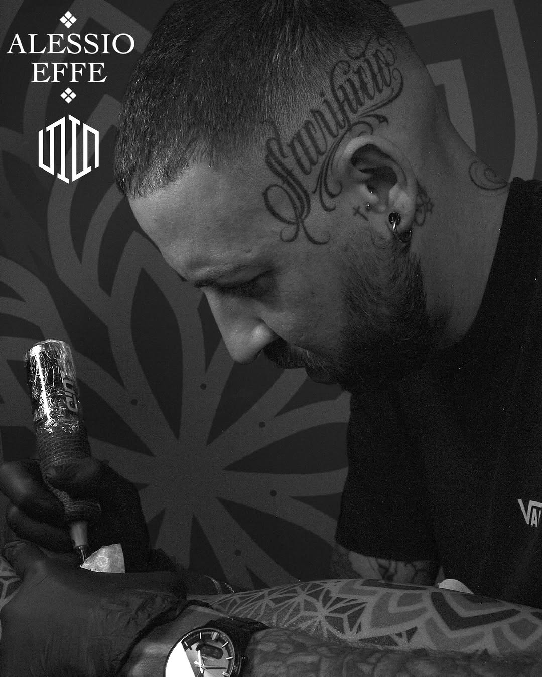 Tattoo artist Alessio Effe displays a large ornamental script tattoo on the side of a client's head in black ink.