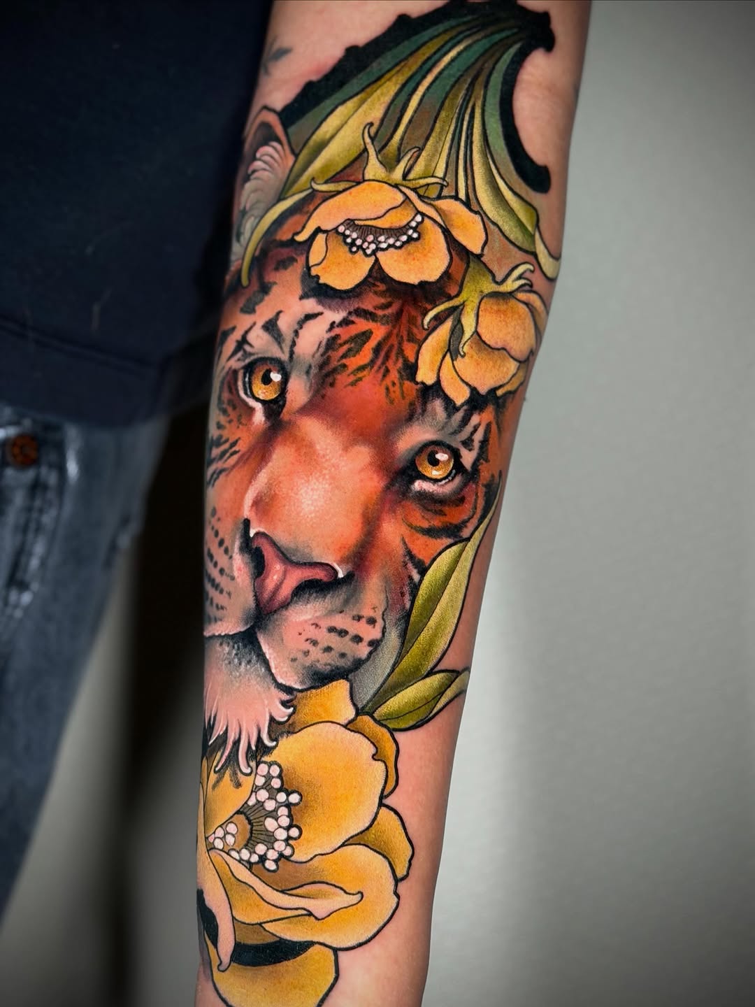 Tiger head with striking amber eyes surrounded by yellow and orange flowers with white details on an arm.