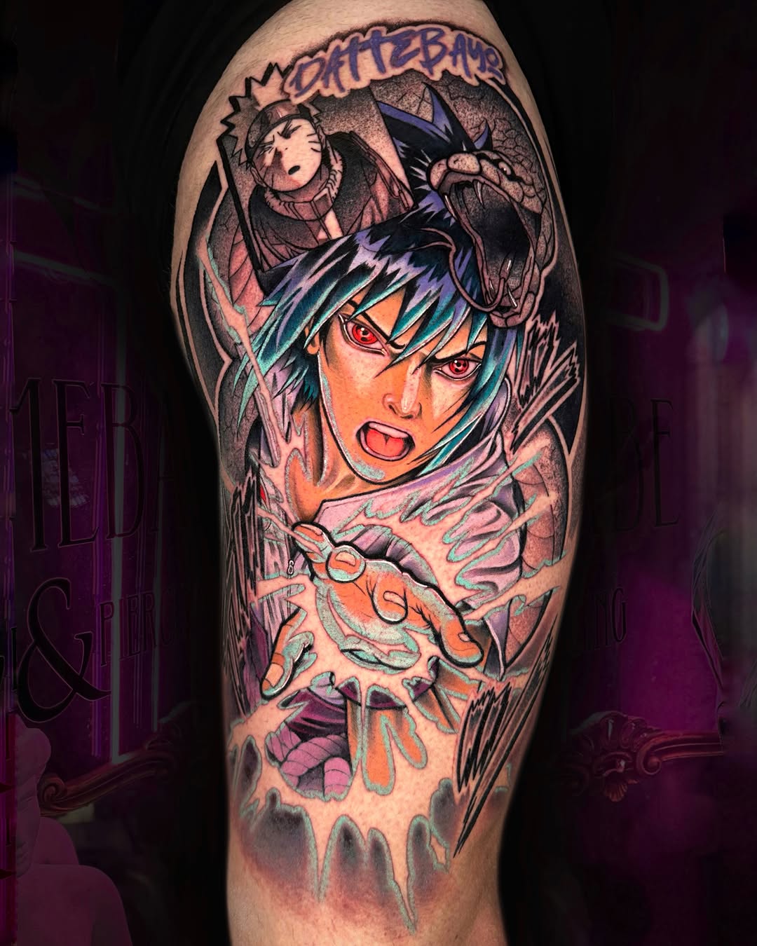 Colorful shoulder tattoo featuring an anime character with blue hair and red eyes, with smaller characters above, rendered in vibrant orange, purple, and teal tones.