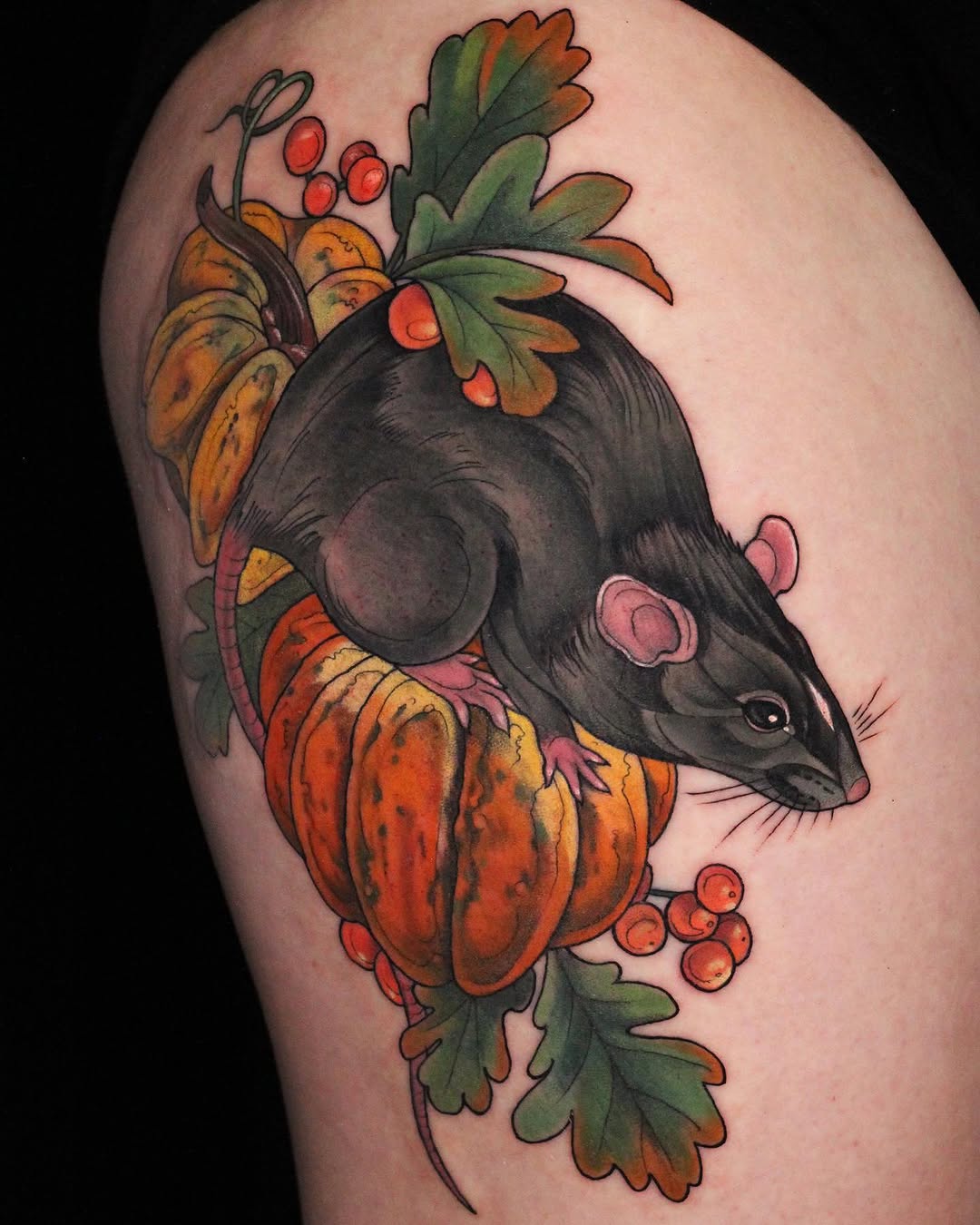 A rat's head adorned with autumn leaves and red berries in orange, green, and black ink on the upper arm.
