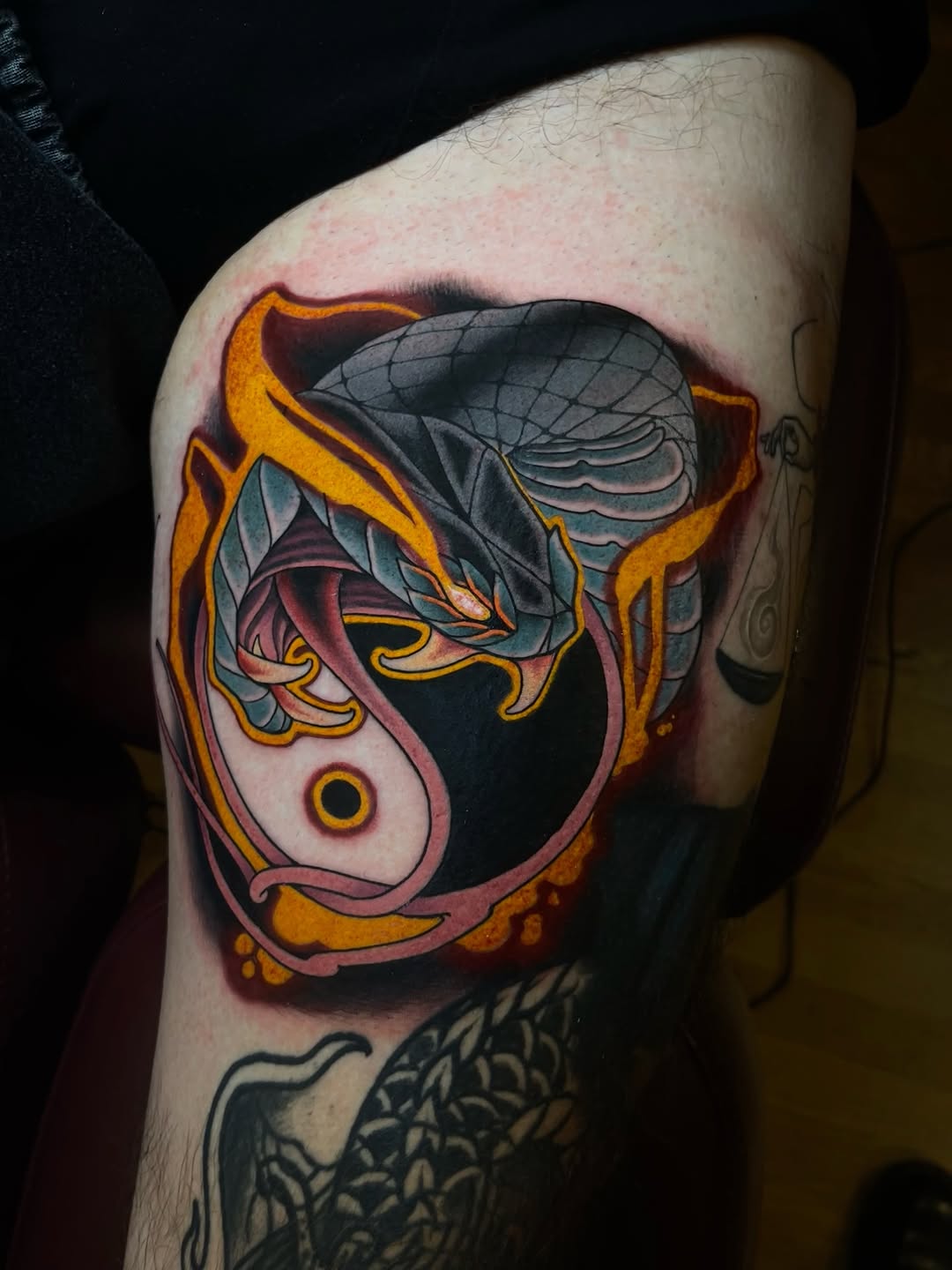 Colorful insect wing tattoo featuring orange, pink, teal, and black hues with anatomical detail on the upper thigh.