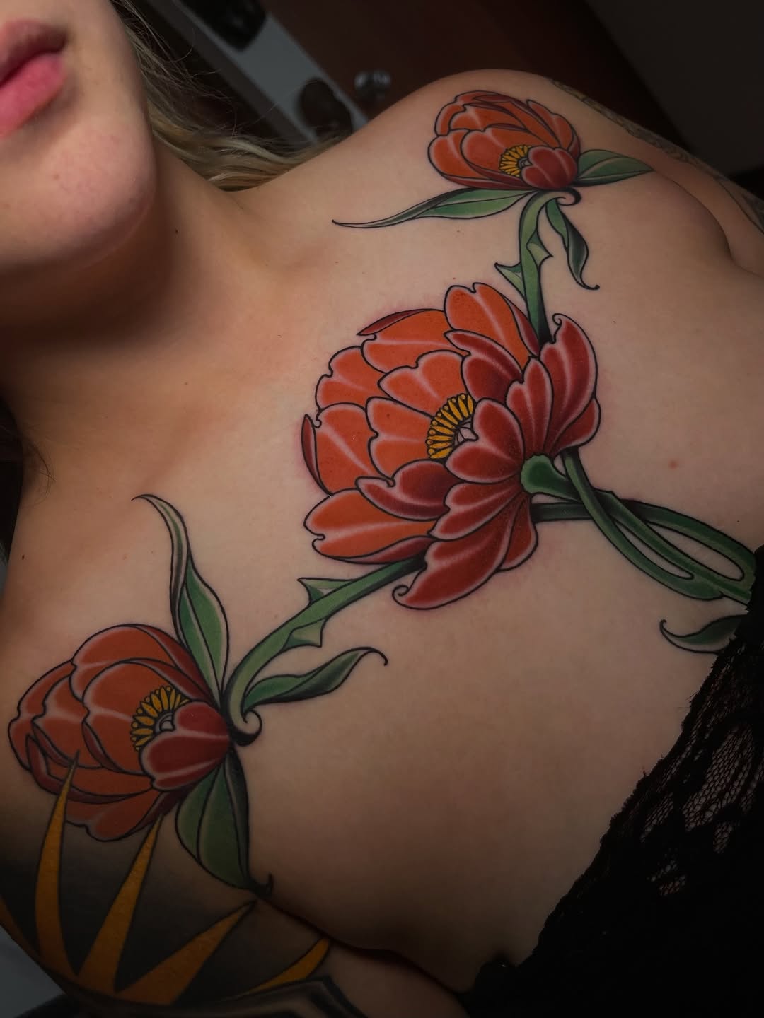 Three red peonies with green stems and yellow centers arranged vertically on the shoulder and upper back area.