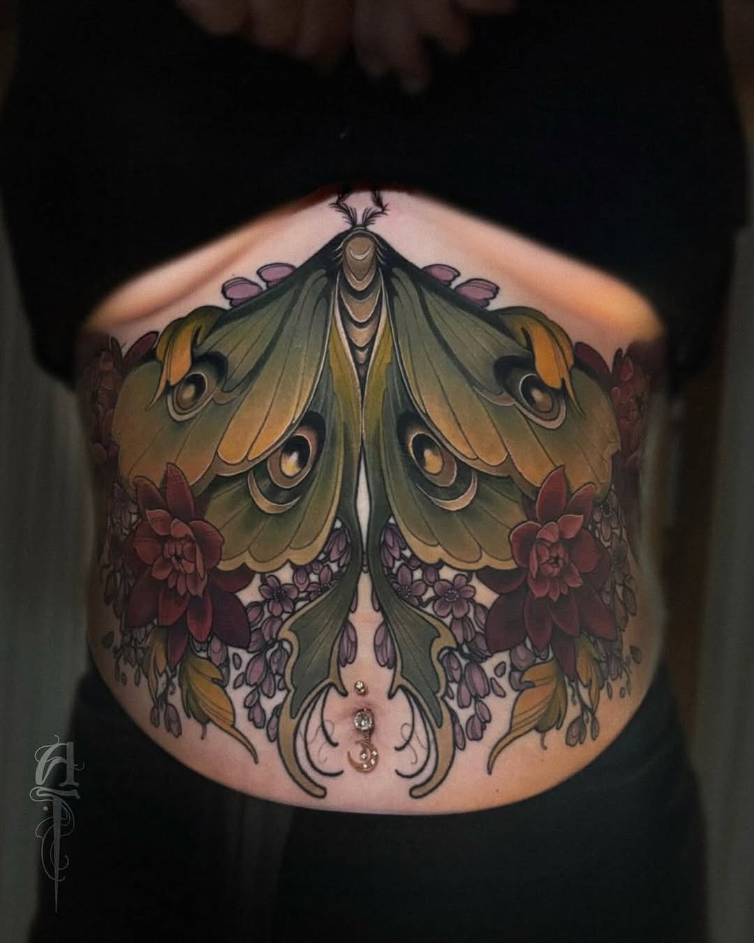 Large symmetrical moth with gold and olive wings, burgundy flowers, and ornamental details centered on the chest and abdomen.