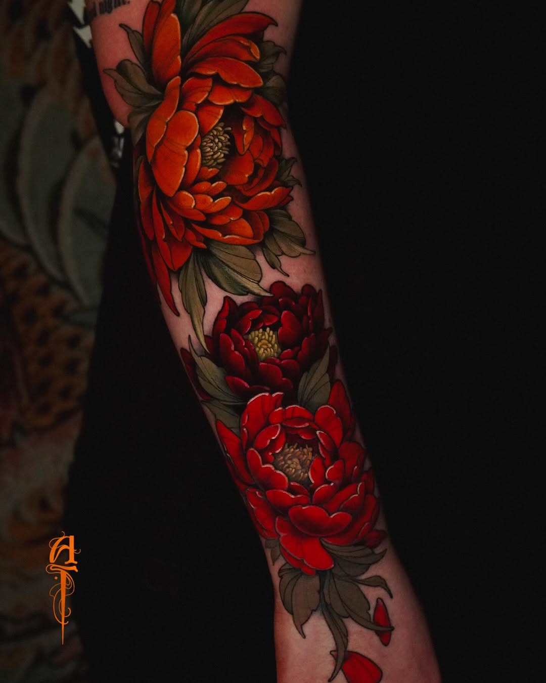 Three large red peonies with green leaves and tan centers arranged vertically on the forearm, against skin-toned background.