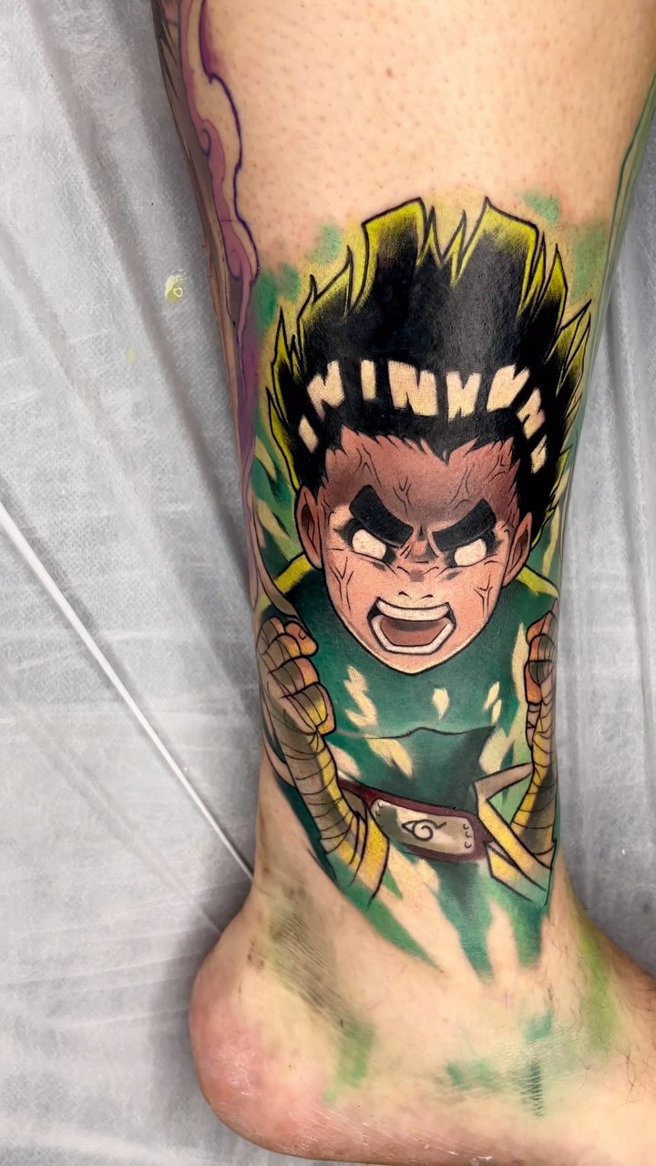 Colorful tattoo on ankle depicting an angry character with spiky black hair, green shirt, and wrapped arms in yellow and brown tones.