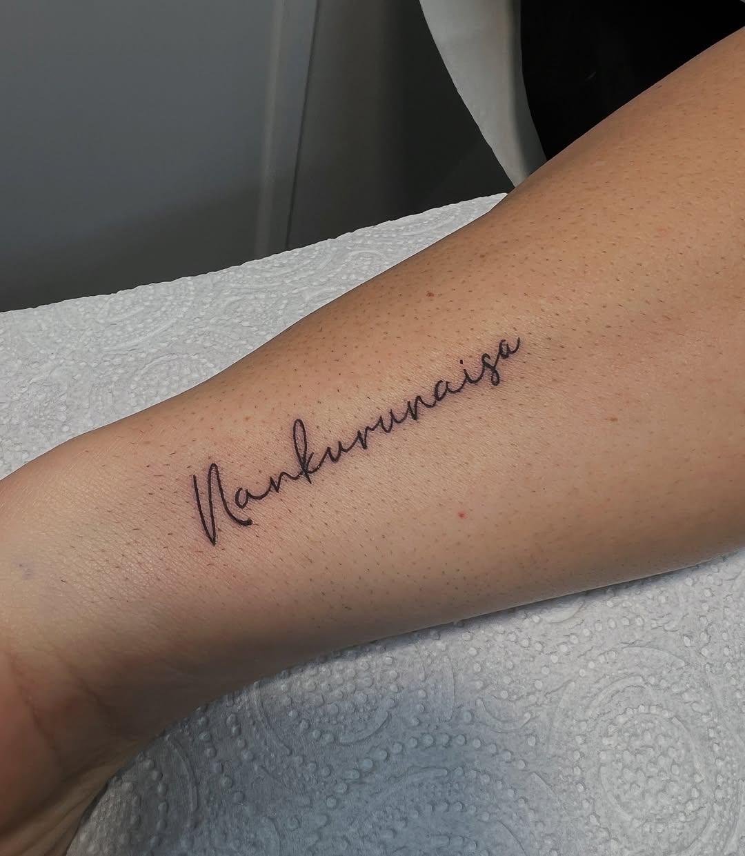 Cursive text reading "Valkyrjaiga" tattooed on an inner arm in dark purple ink.