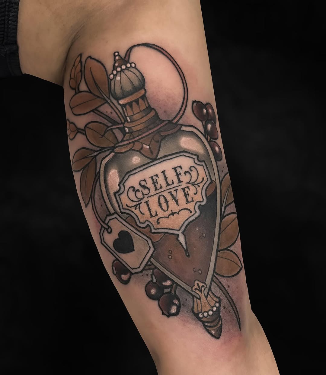 Ornate potion bottle tattoo with "Self Love" text, bee and botanical elements, rendered in brown and black ink on an upper arm.