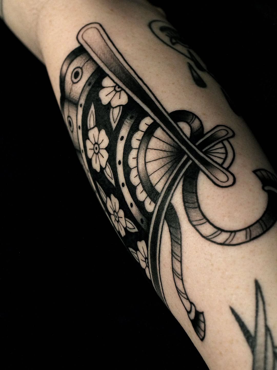 Moth tattoo with floral and geometric patterns on the forearm, rendered in black ink with detailed linework and shading.