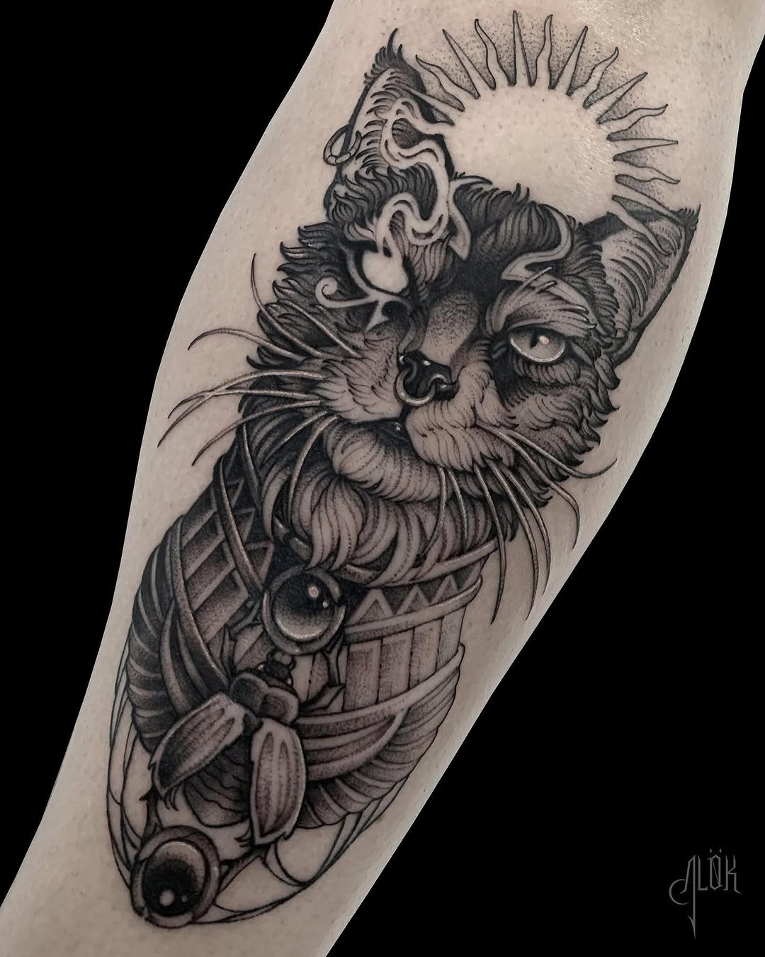 Detailed monochrome tattoo on the forearm featuring a bearded face with radiating spikes, ornate armor, and botanical elements including flowers and leaves.