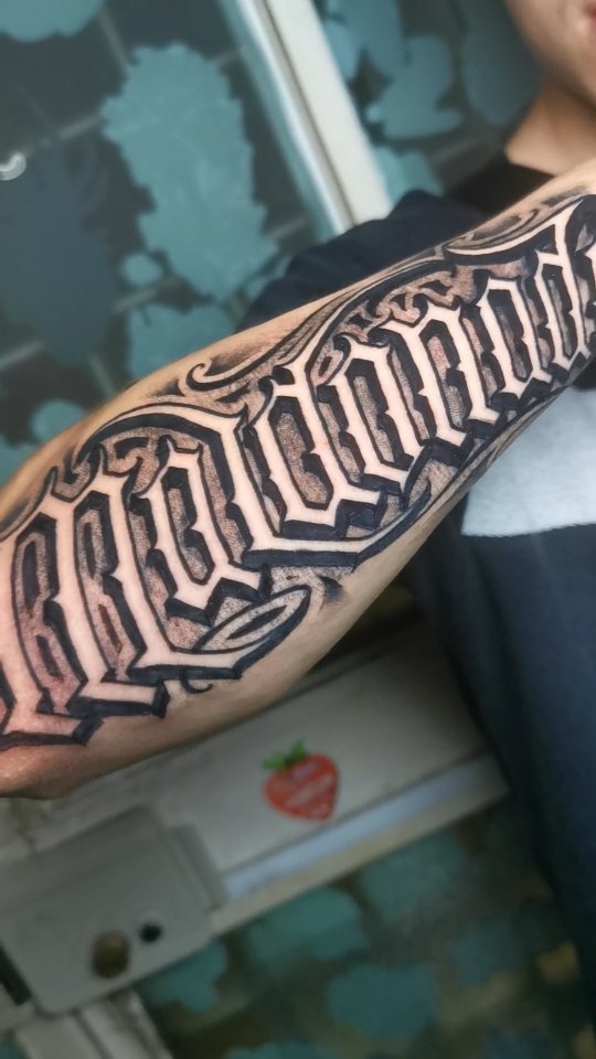 Geometric patterned tattoo on the forearm featuring interlocking hexagonal shapes in black ink on skin.