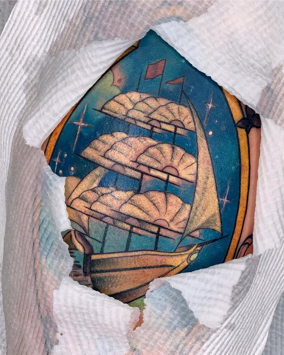 Colorful arm tattoo featuring three stacked baskets with wheat, a teal background, flags, and golden accents in warm earth tones.