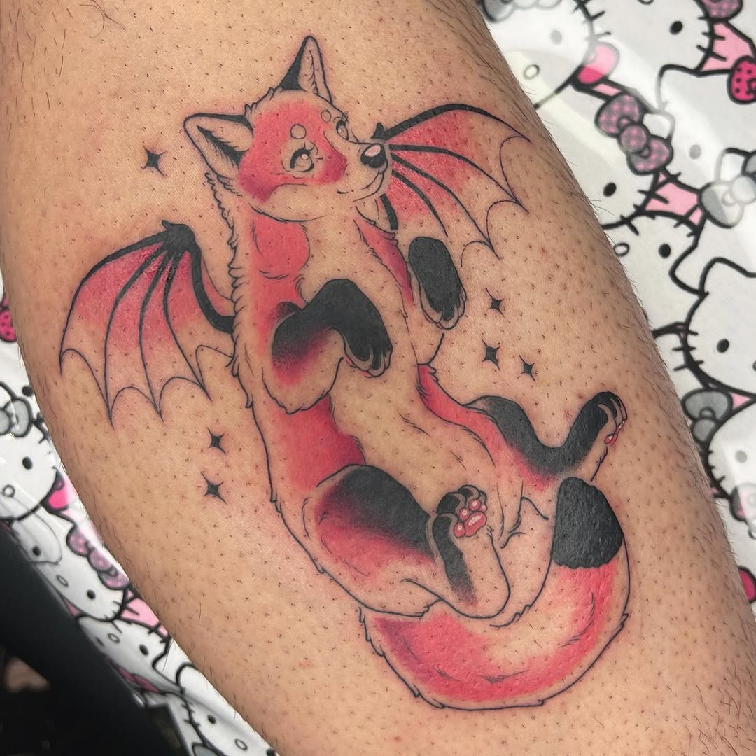 Red and black bat-winged cat with pink accents and small stars tattooed on an upper arm.