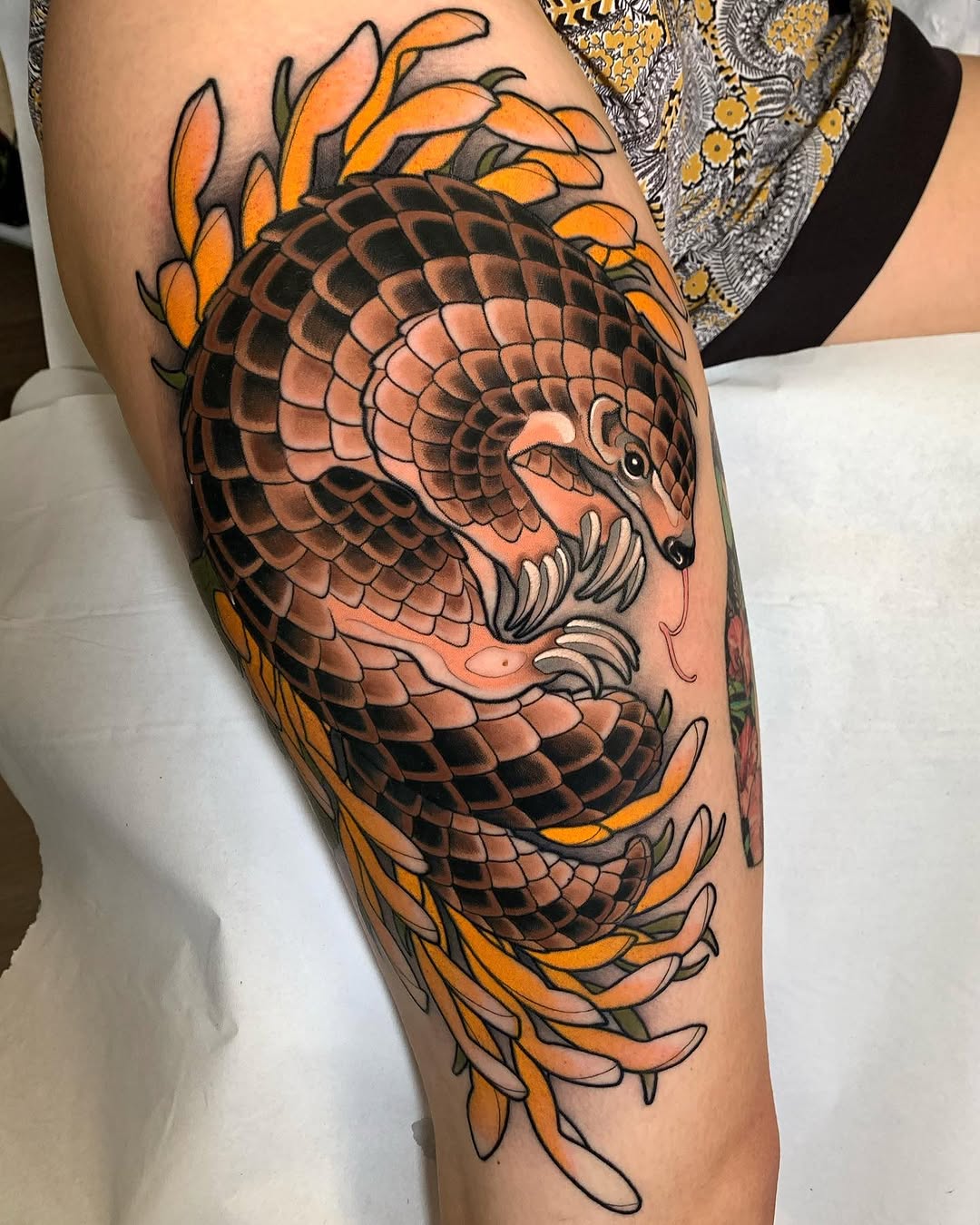 Dragon head with scaled body and orange flame-like foliage adorning the thigh and leg area in orange, black, and tan colors.