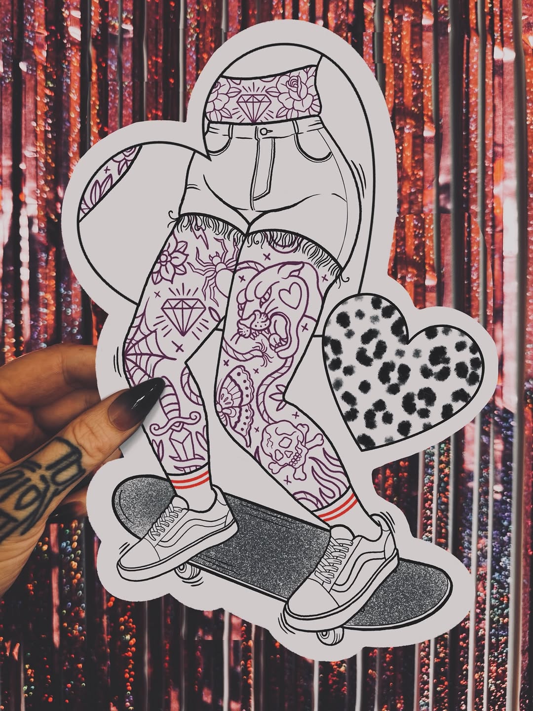 White sticker illustration of a tattooed woman in patterned shorts and sneakers sitting on a skateboard, with heart designs, held against a red sequin background.