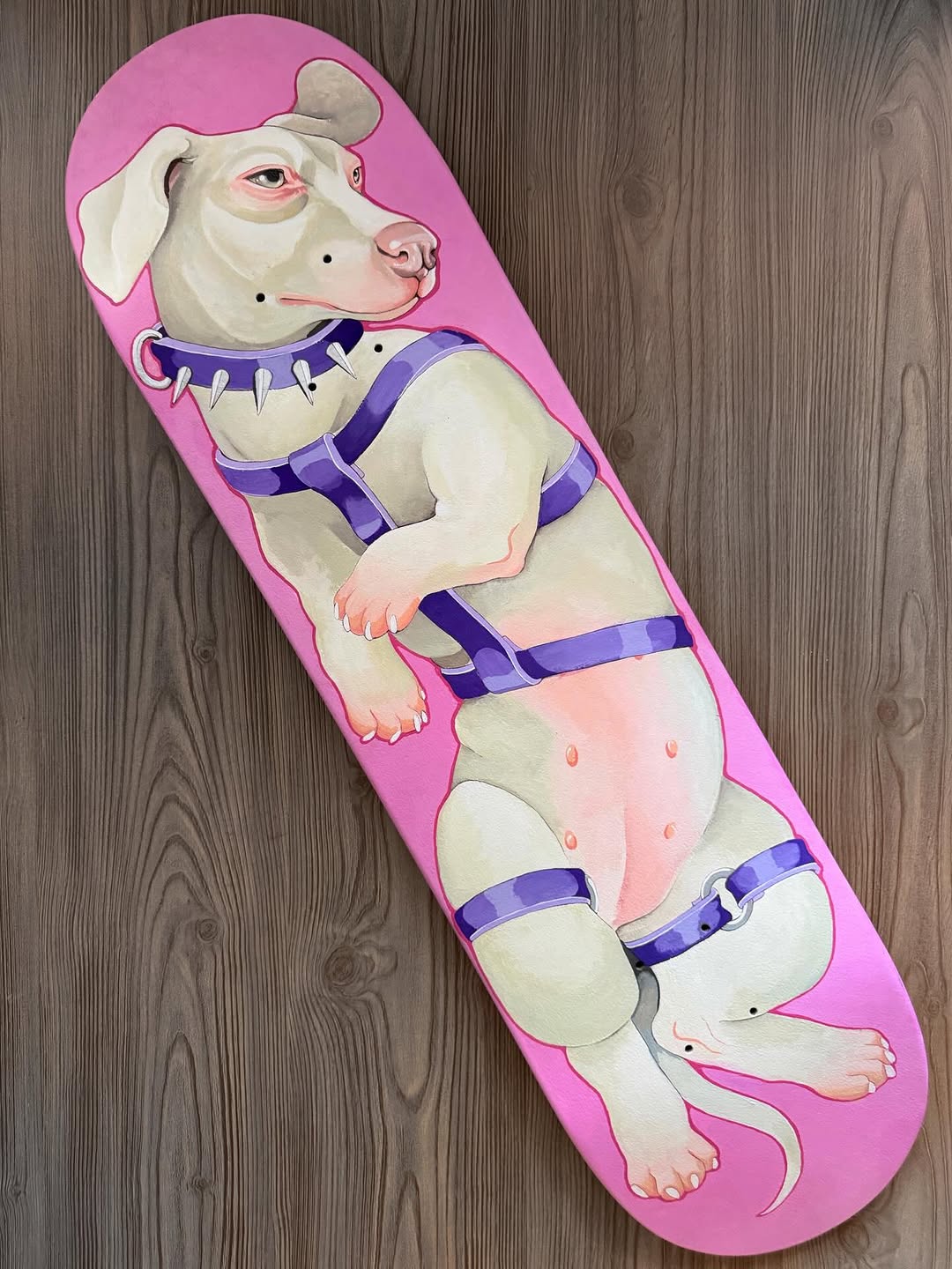 White anthropomorphic dog character wearing purple harness and collar on pink skateboard deck with detailed shading and color work.
