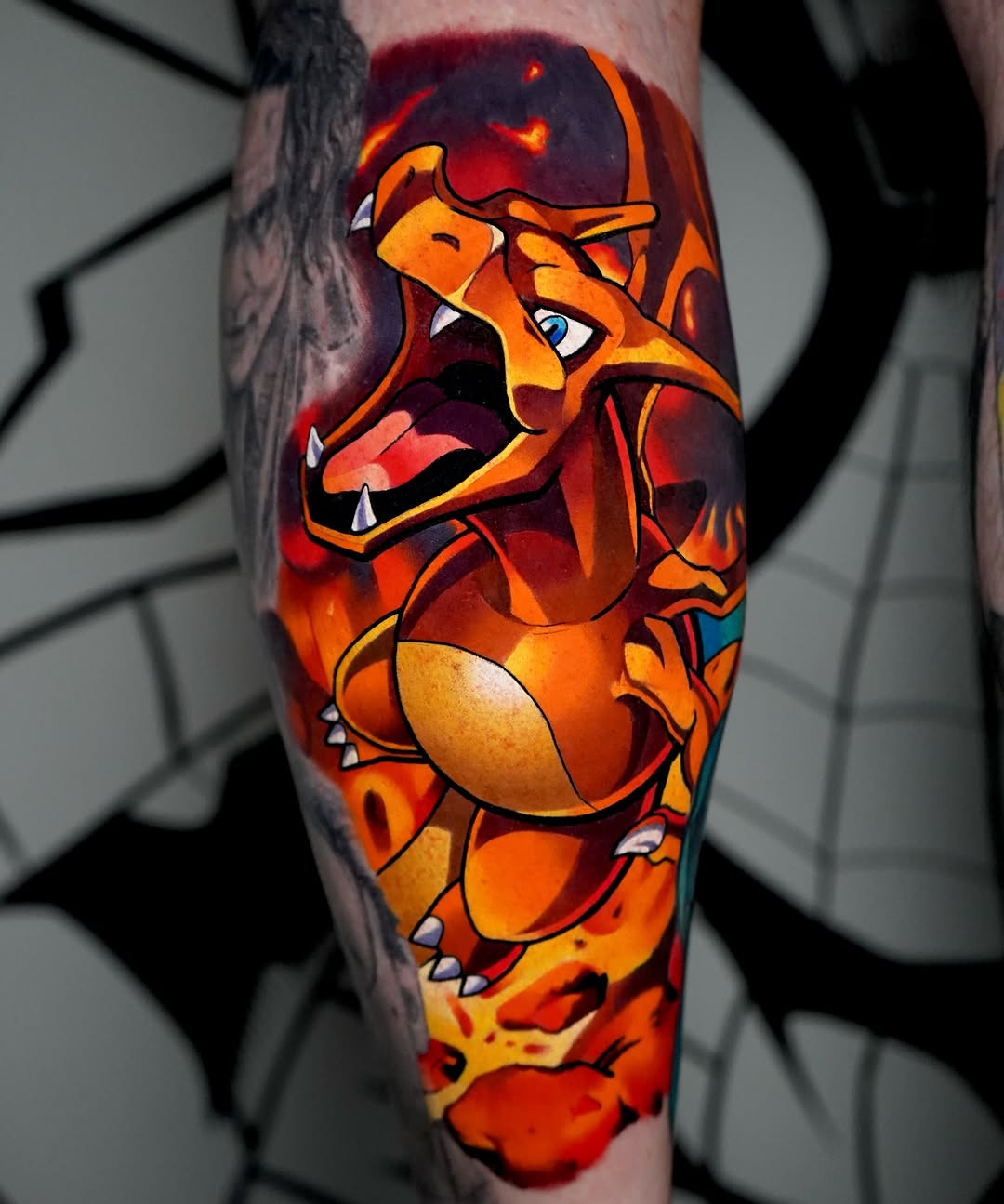 Colorful tattoo of a roaring orange and red dragon with extended claws on the inner forearm, featuring vibrant yellow, orange, and deep red hues.