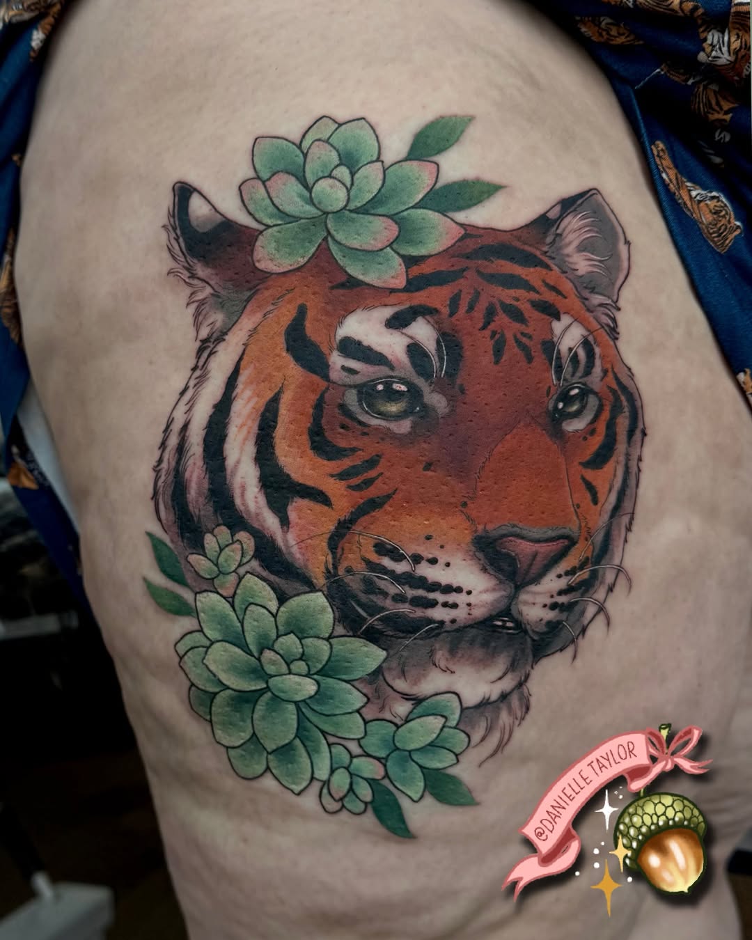 Tiger head with green succulent plants positioned on the shoulder, featuring orange and black coloring with detailed facial features and whiskers.