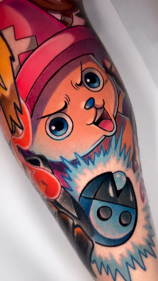 Colorful tattoo on forearm featuring a bearded character with red hat and blue owl design, rendered in orange, red, pink, and blue tones.