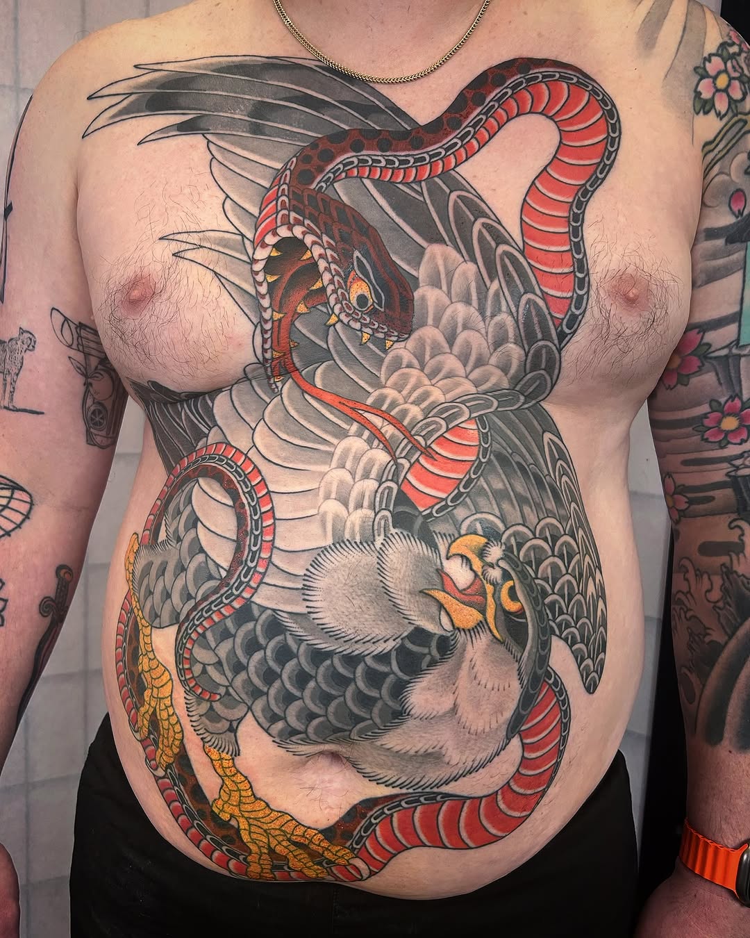 Large chest and abdomen tattoo featuring a dragon with red scales, a white-furred beast, and yellow reptilian creature intertwined with intricate detail work.