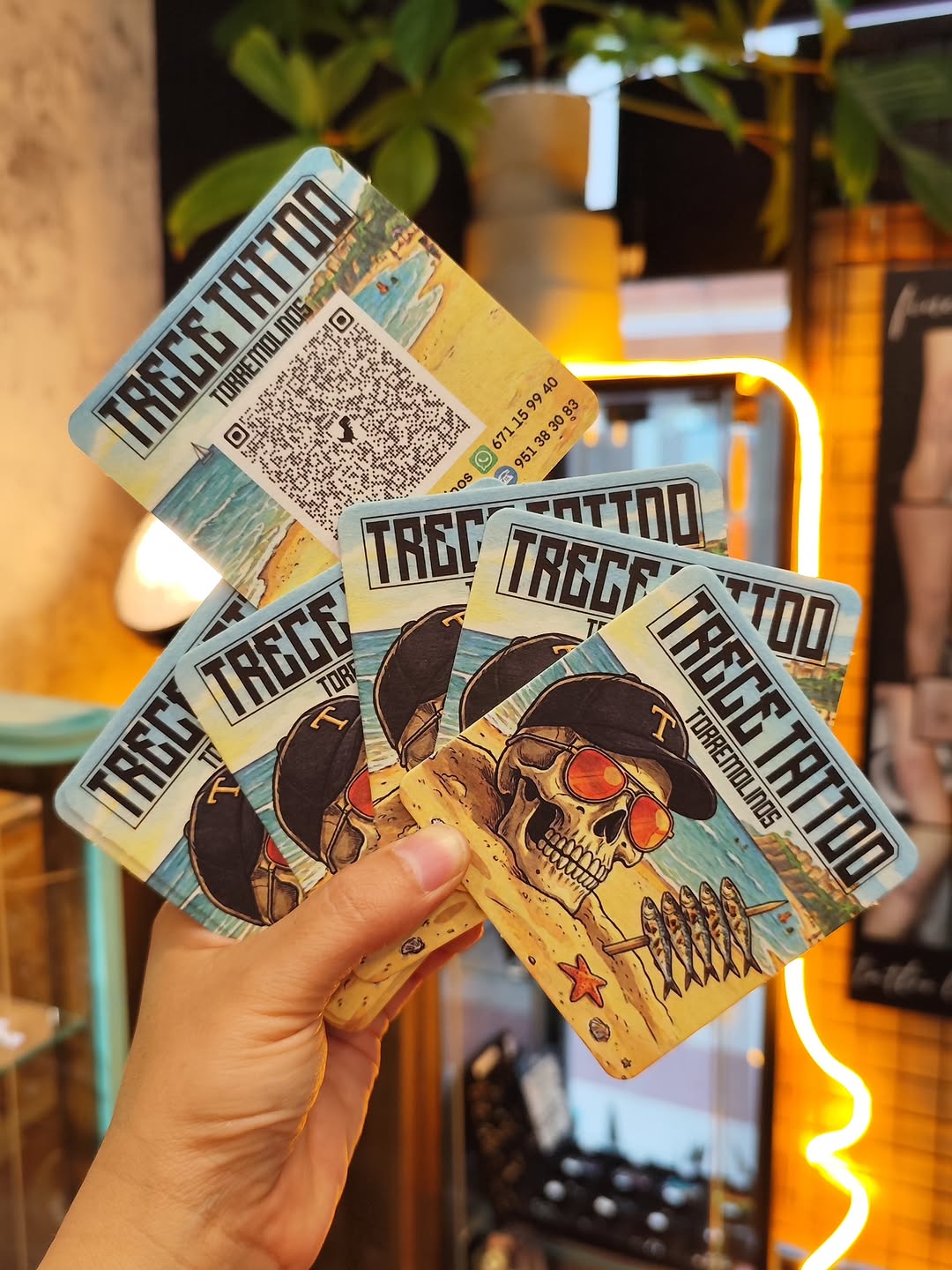 Hand holding multiple flash cards displaying skull designs with cowboy hats, red eyes, and desert imagery in yellow and brown tones.