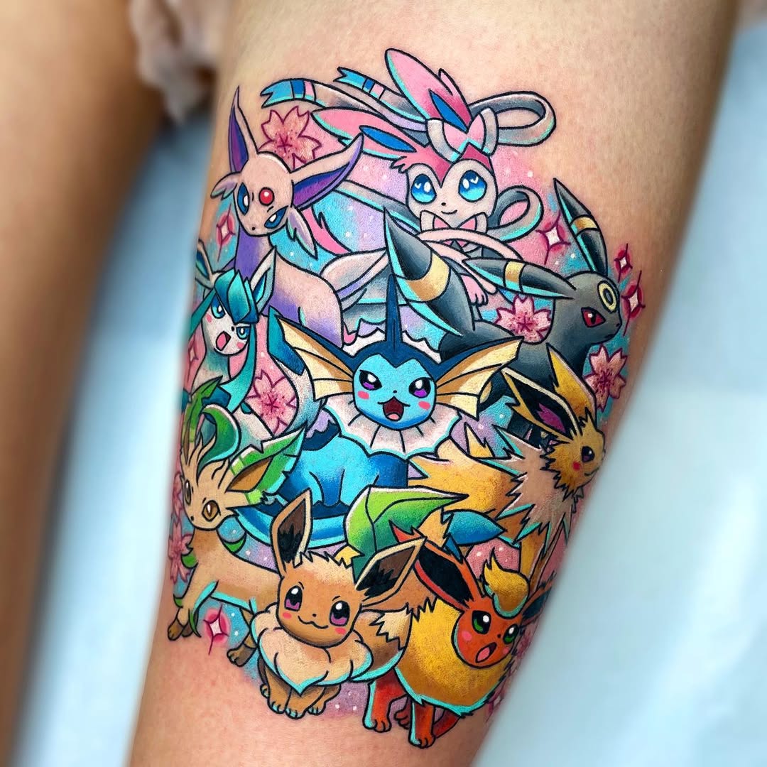 Colorful tattoo on the upper leg featuring multiple small creatures with large eyes surrounded by pink flowers and gems in blue, purple, yellow, and pink tones.