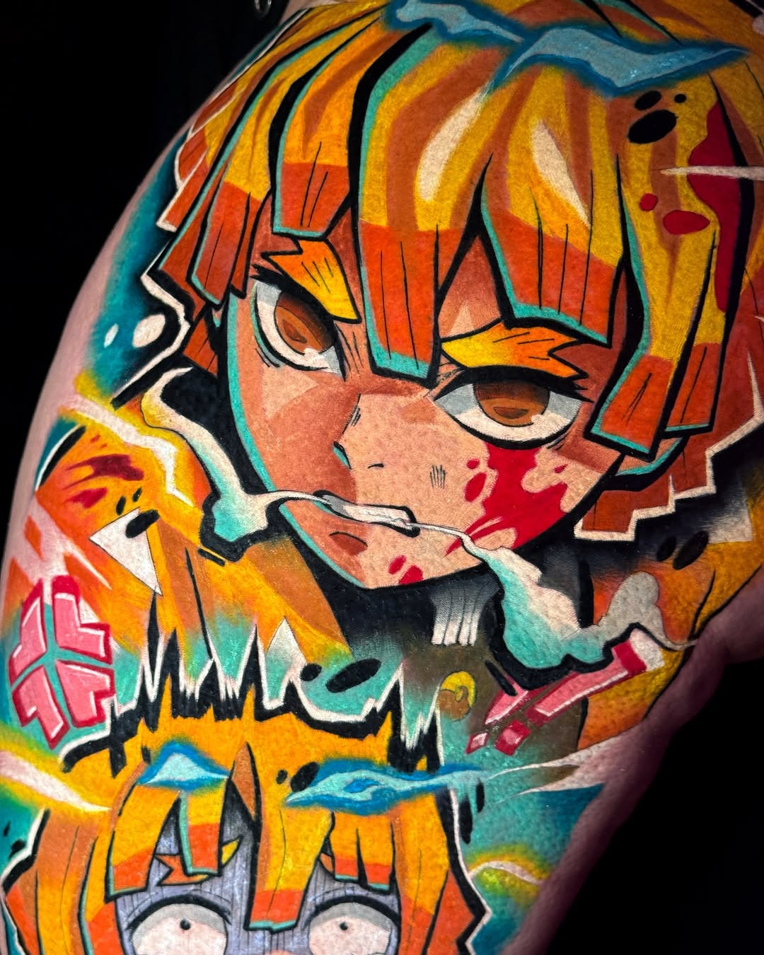 Colorful shoulder tattoo featuring an anime-style character with orange hair, large expressive eyes, and layered clothing in vibrant yellows, oranges, teals, and reds.