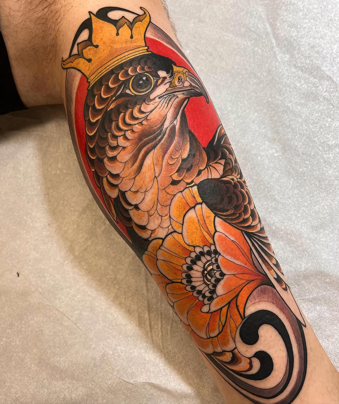 Colorful koi fish tattoo on forearm featuring orange and black scales, red background panel, and decorative swirl detail at the wrist.