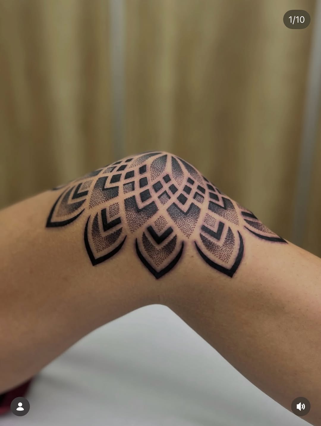 Geometric mandala tattoo with nested diamond and leaf patterns filled with dotwork, placed on upper arm in black and gray ink.