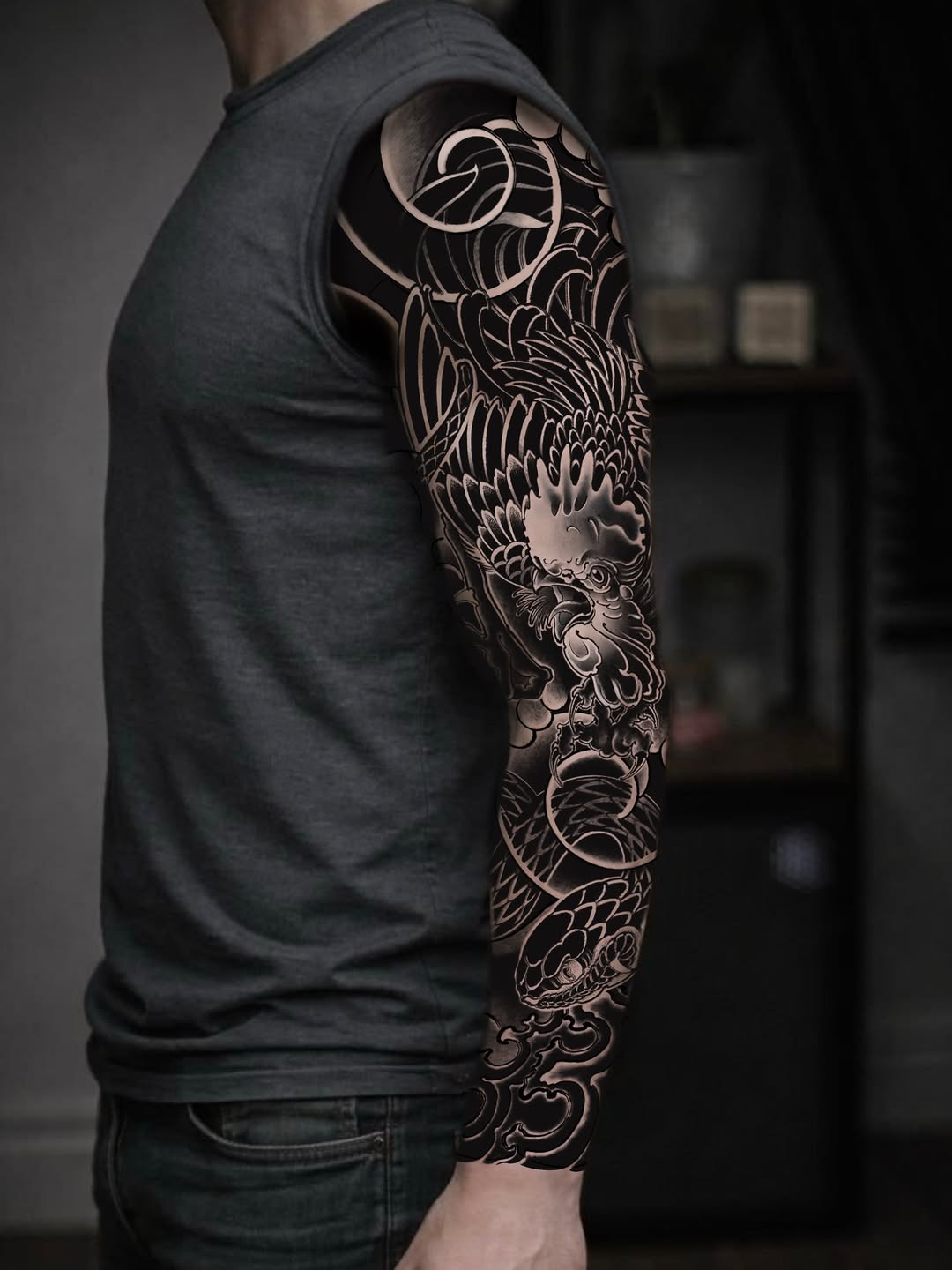 Full-sleeve arm tattoo featuring an ornate dragon with detailed scales, scrollwork, and decorative flourishes in black and grey ink.