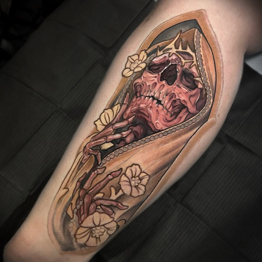 Skull tattoo with burgundy and tan shading, cream flowers, and decorative beading on the forearm.