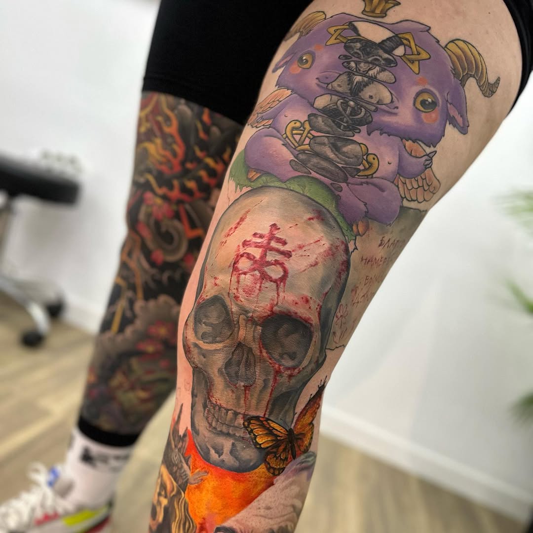 Colorful leg sleeve tattoo featuring a purple demon mask with butterflies above a skull with red markings and orange base elements.