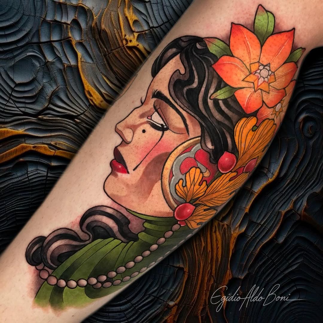Portrait of a woman with dark hair in profile facing left, adorned with red and orange flowers and green leaves, wearing a pearl necklace on the forearm.