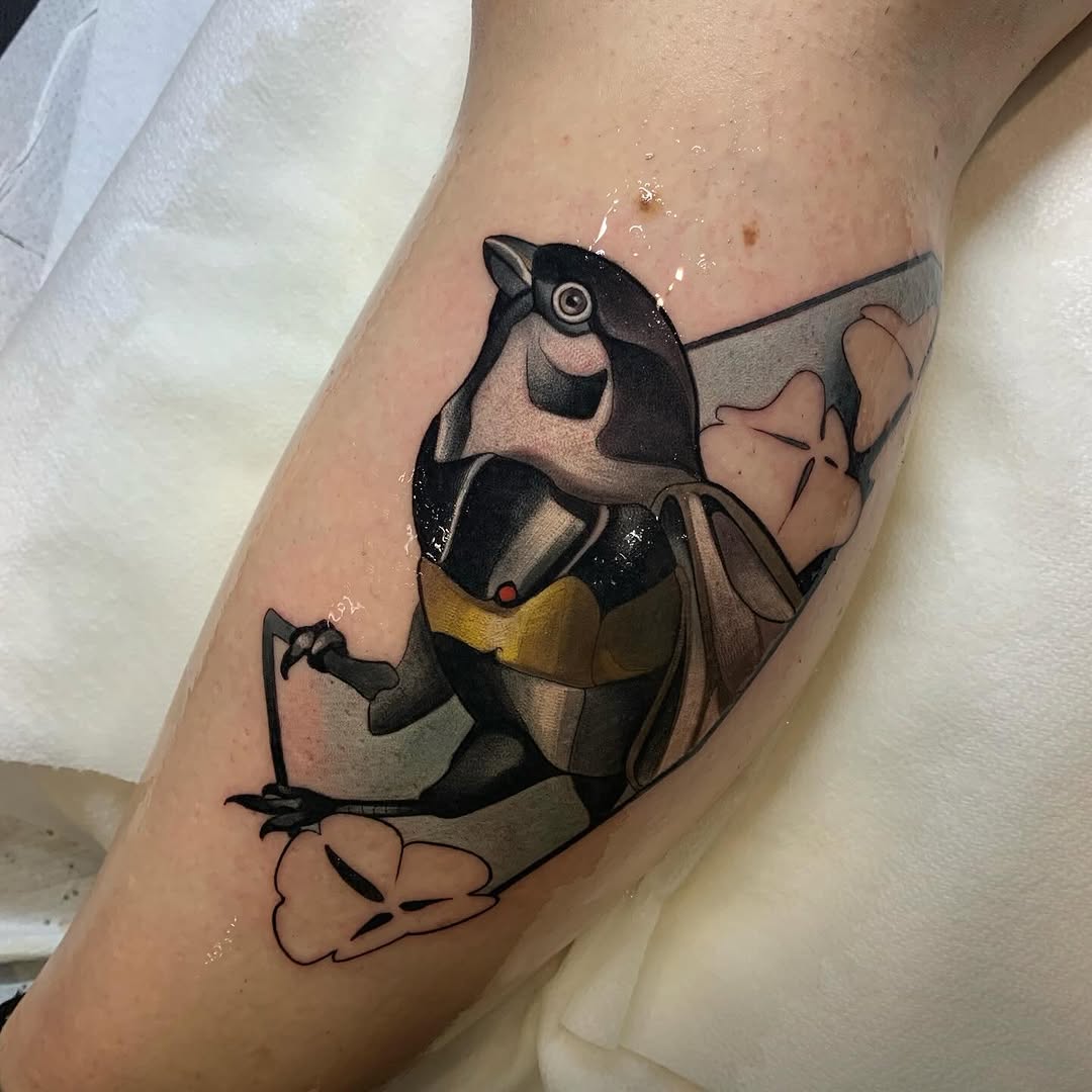 Cartoon raccoon character wearing a yellow vest and harness, tattooed on the upper arm in black, gray, and yellow ink.