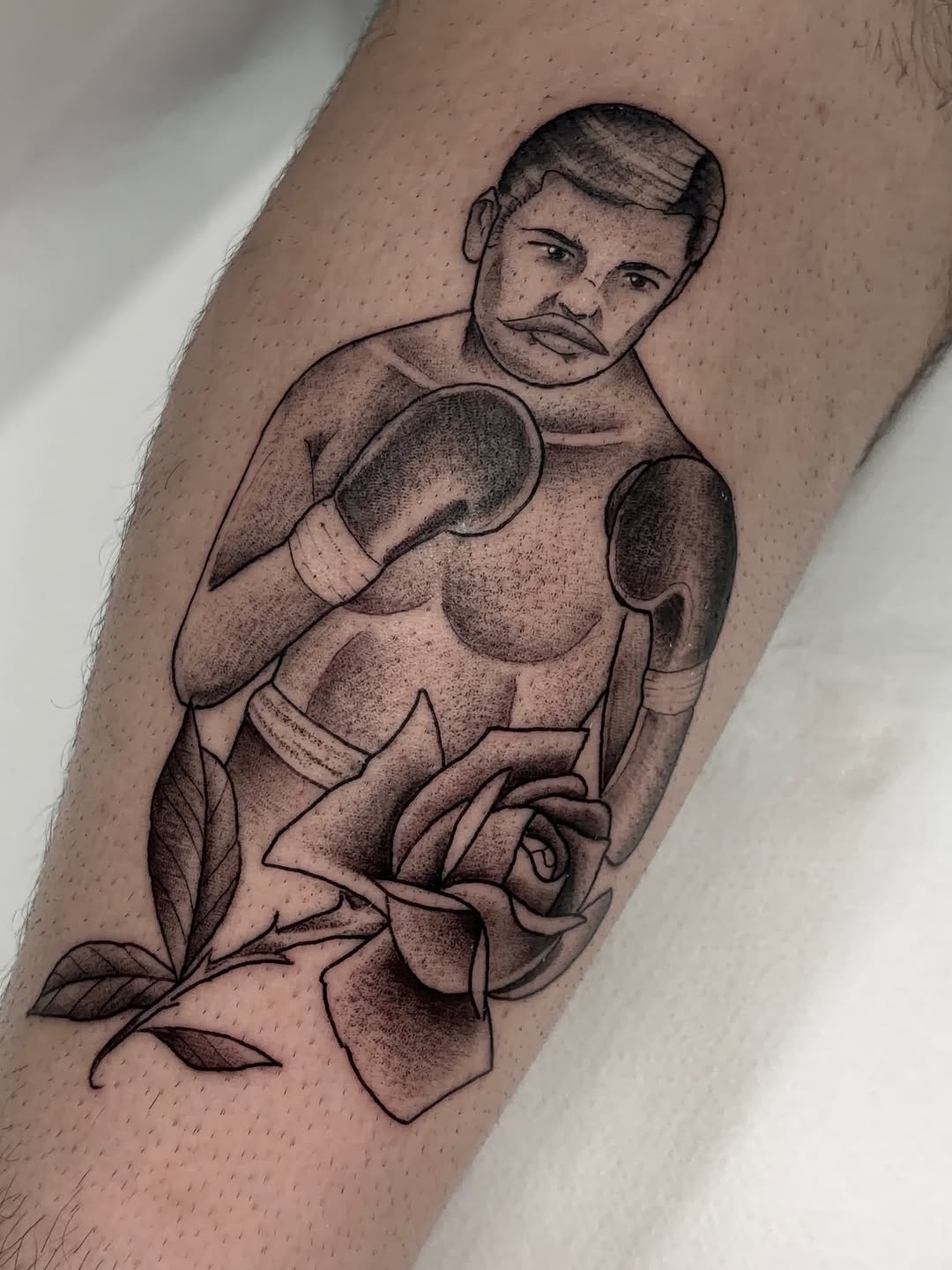 Boxer figure with boxing gloves and rose flower displayed on upper arm in black ink with shading.