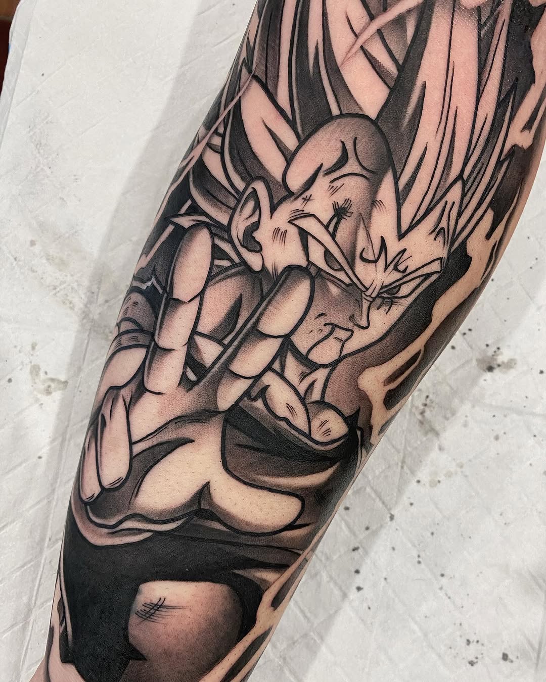 Demon character tattoo on forearm featuring sharp facial features, flowing hair, muscular upper body, and dark shading with black ink details.