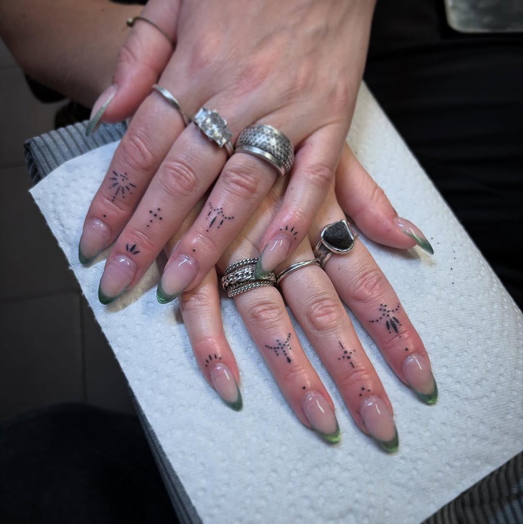 Small black dot and line constellation tattoos on multiple fingers and hands, displayed on natural skin with silver rings.