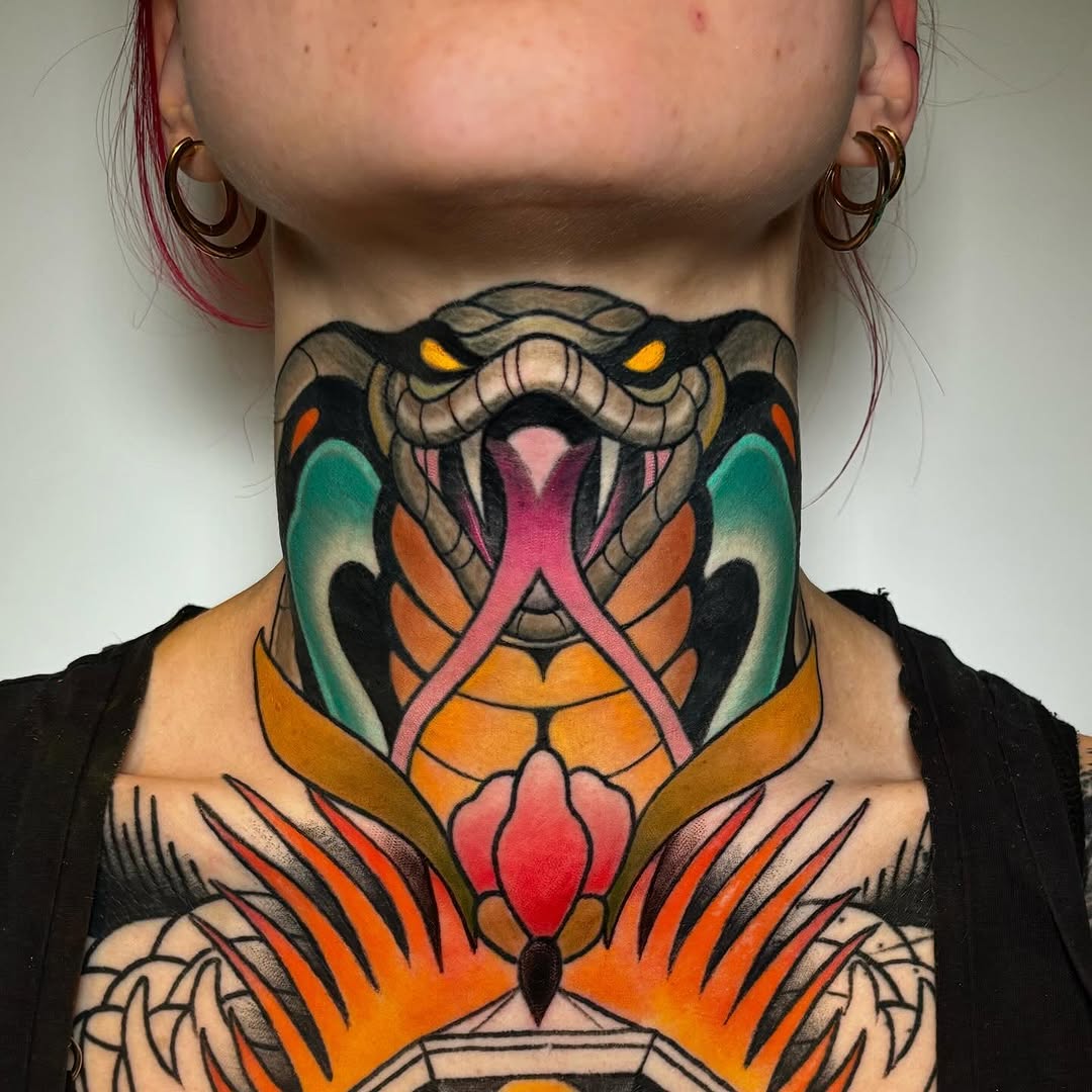 Colorful neck tattoo featuring a horned creature with yellow eyes, pink tongue, and orange wings, extending down the chest in vibrant reds, greens, and blacks.