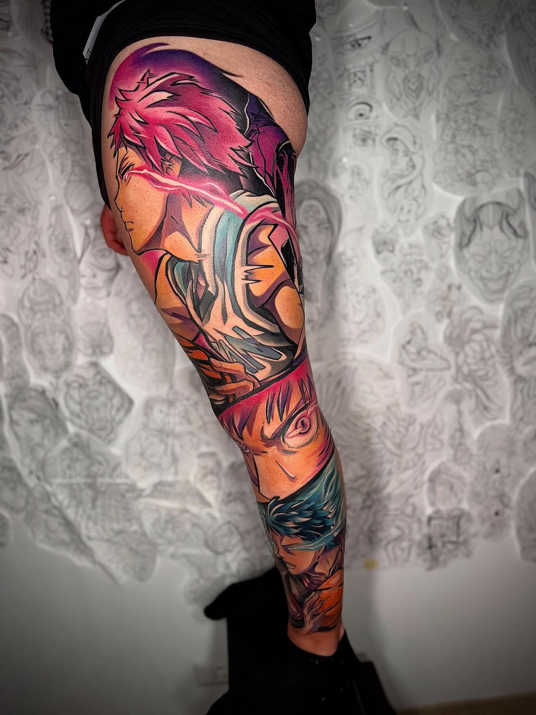 Full-leg tattoo sleeve featuring multiple stylized faces with flowing hair in vibrant pink, orange, blue, and purple tones with black line work.