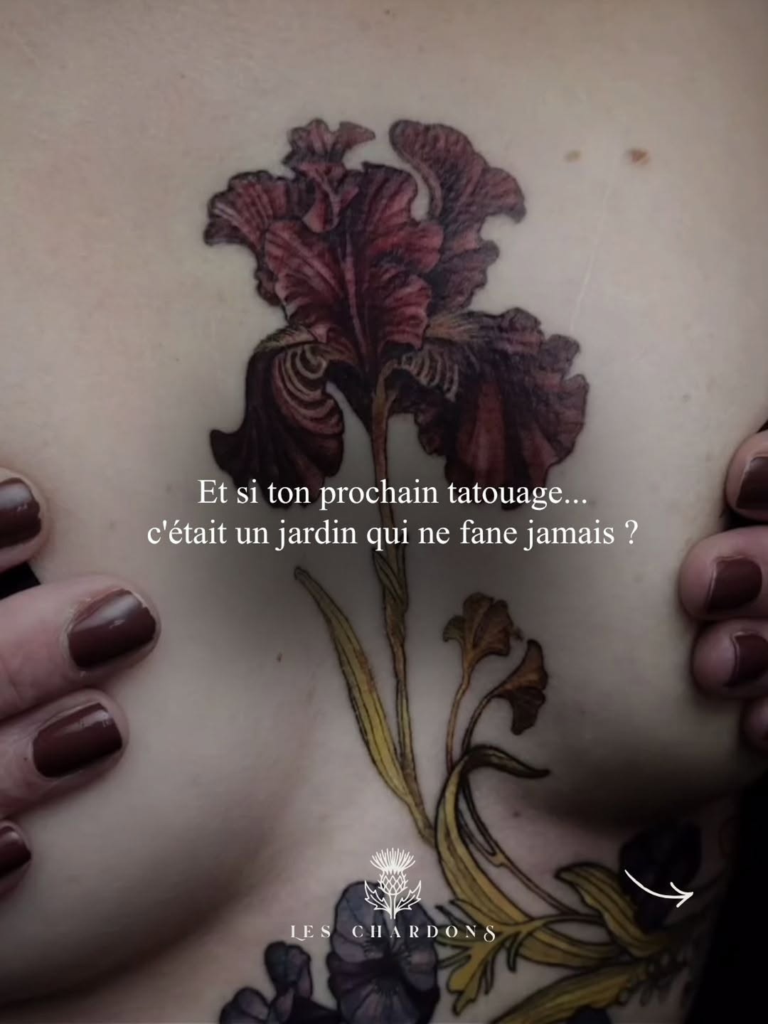 Deep burgundy iris flower with green stem and leaves tattooed on upper arm, displayed next to matching manicured nails.