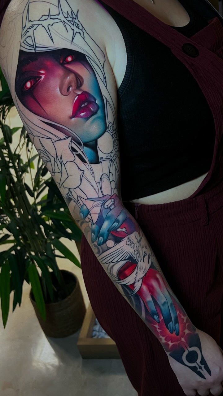 Full sleeve tattoo featuring a female face with glowing eyes and red lips, abstract line work, and colorful watercolor elements in pink, blue, and red tones.