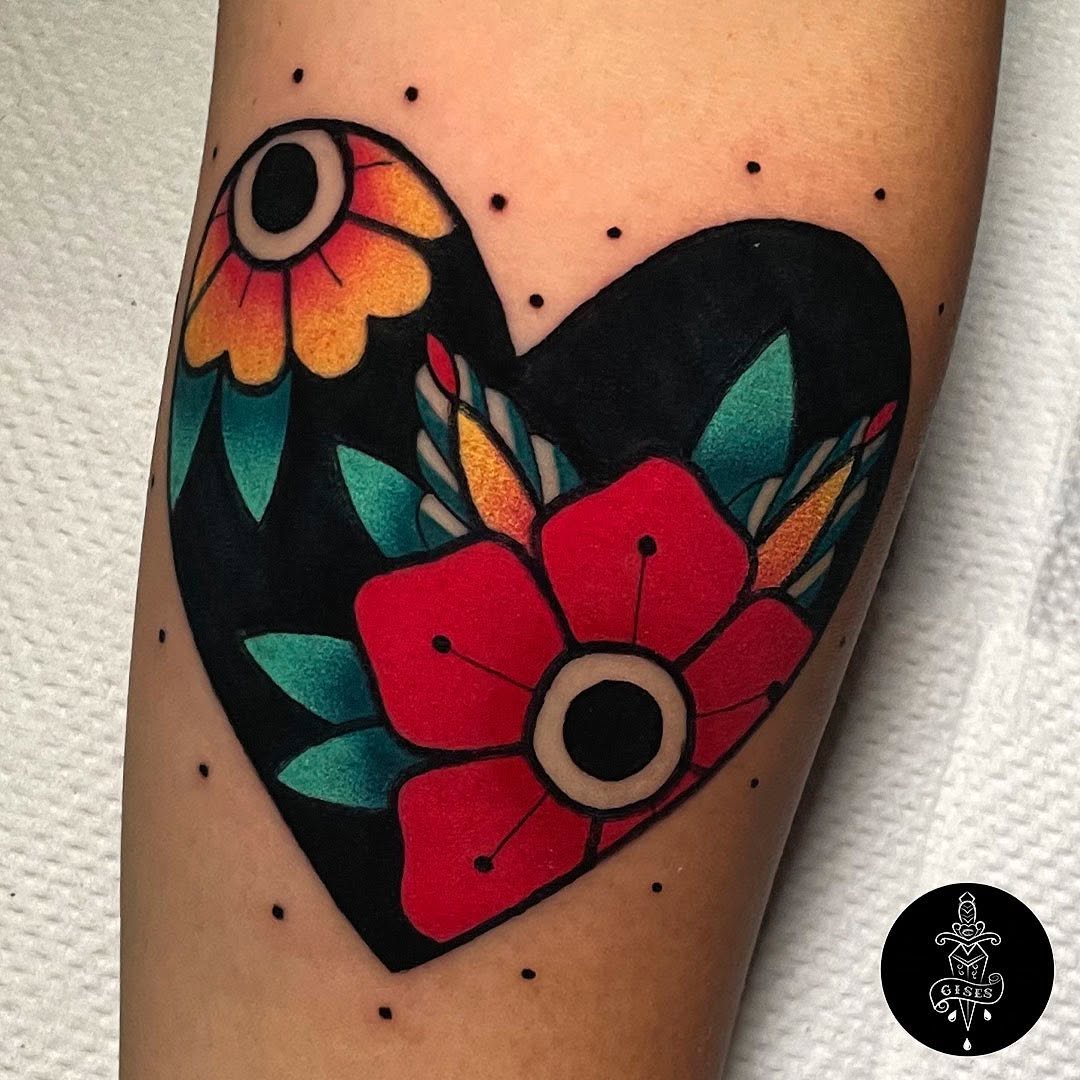 Heart-shaped tattoo with a yellow and orange flower on the upper left and a red flower on the lower right, surrounded by teal leaves and black outlines on the forearm.
