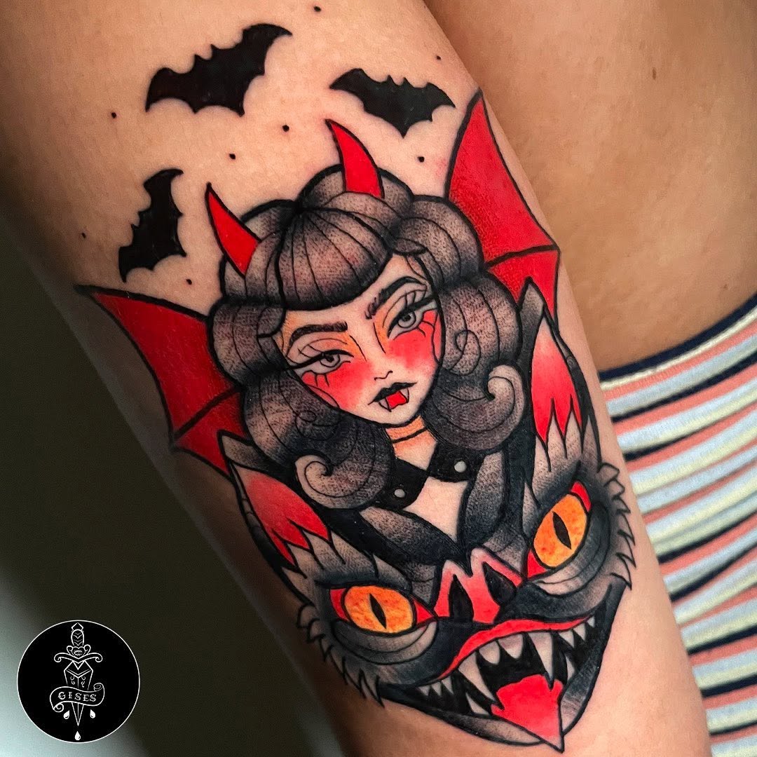 Colorful shoulder tattoo featuring a demon girl with red horns and wings, orange cat eyes, gray hair, and flying bats above.