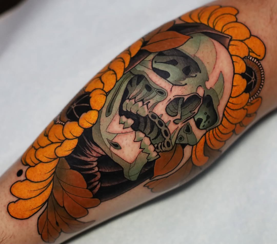 Colorful arm tattoo featuring two overlapping skulls with a pink bonnet, surrounded by orange and brown floral elements on the forearm.