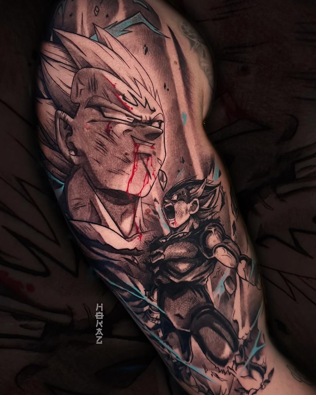 Leg tattoo featuring a spiky-haired character's head with red accents and a smaller armored figure below, rendered in grayscale with blue highlights.